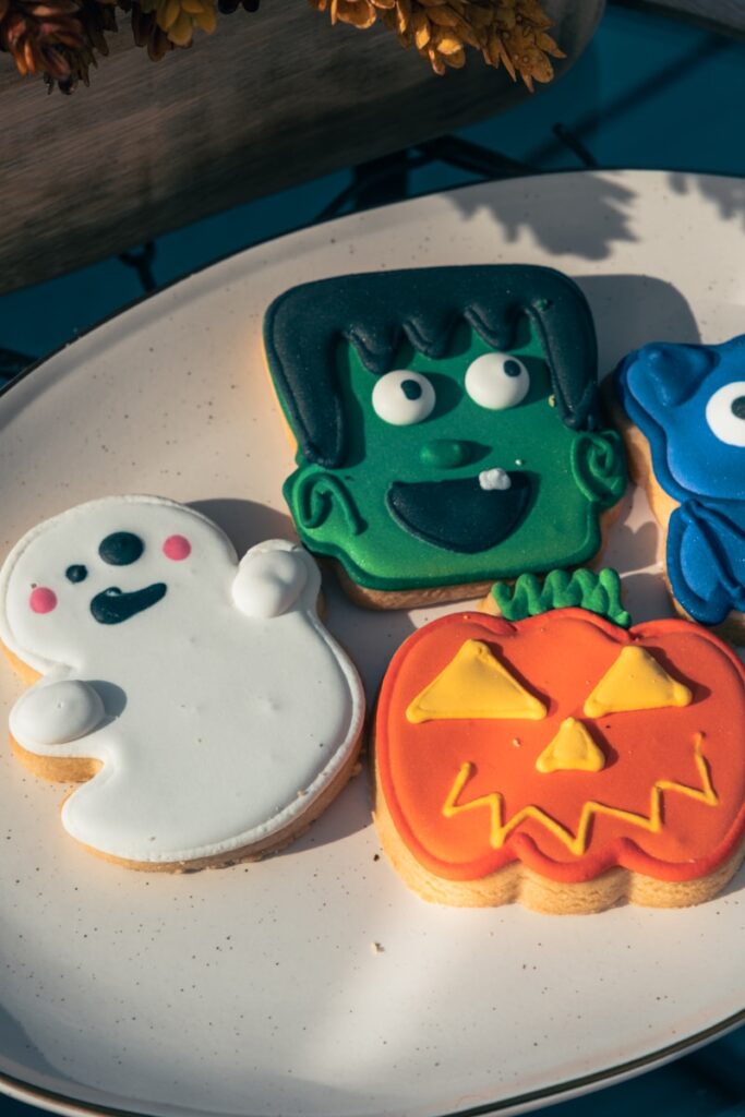Plate of Halloween cookies shaped like a ghost, pumpkin, and Frankenstein, representing calm, creative ways for anxious kids and families to enjoy Halloween.