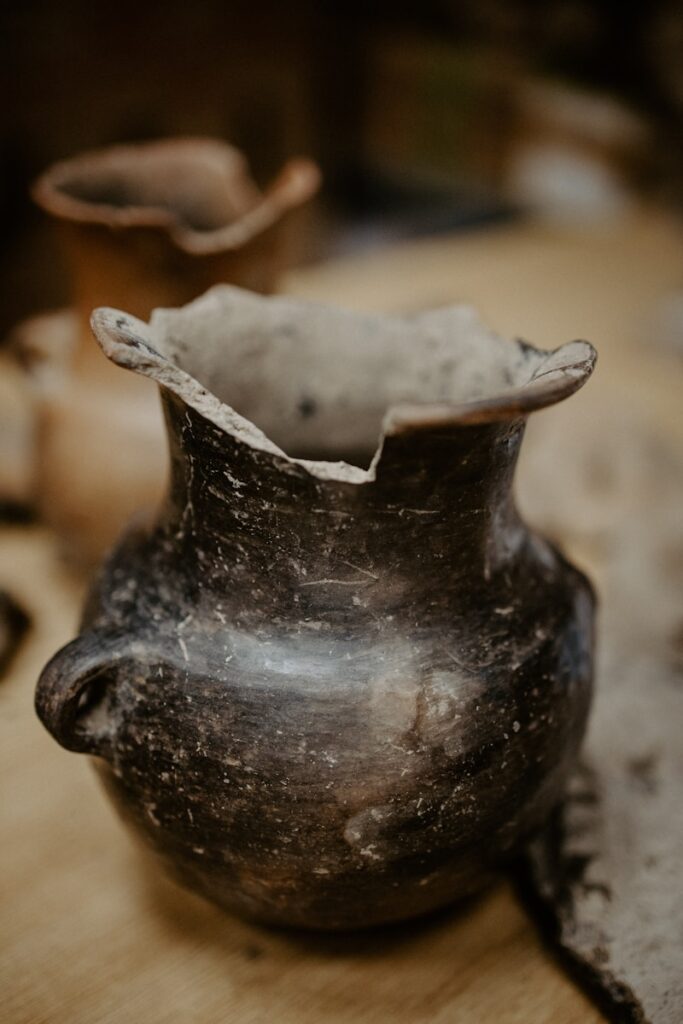A close-up of a chipped ceramic vase, showing its cracks and texture in soft natural light.