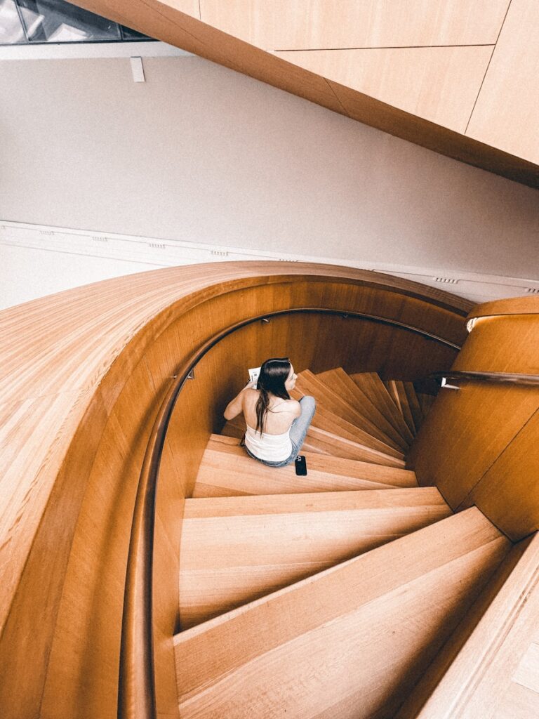 Woman sitting on a spiral staircase, reflecting during a pause in New Year's resolutions