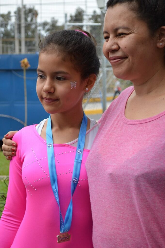 Parent with arm around daughter's shoulder after competition, supporting her achievements.
