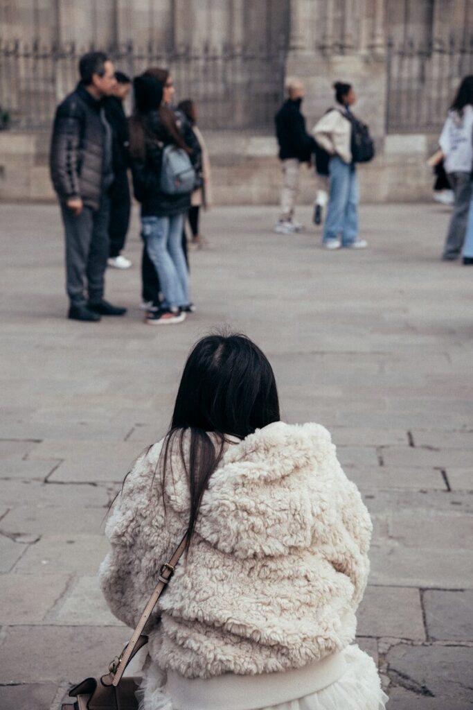 Young woman looking toward a group of peers, representing fear of judgment and social anxiety in everyday situations
